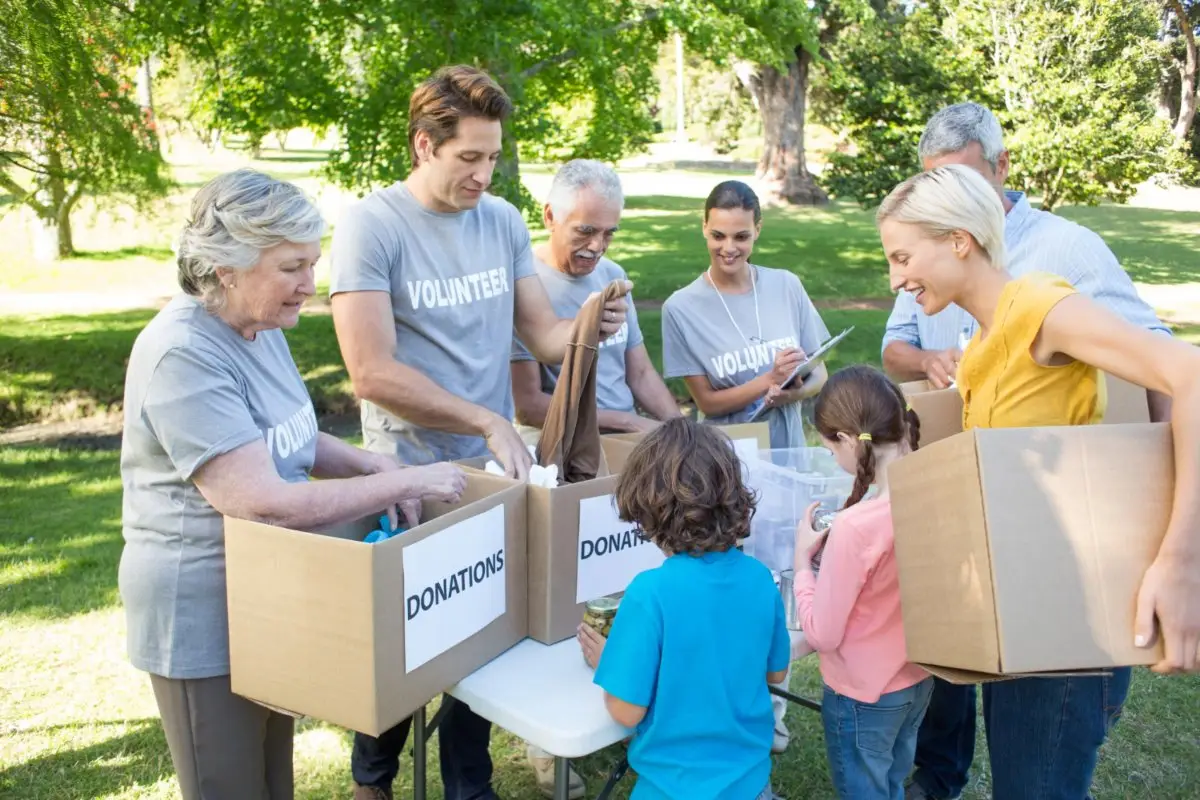 Group of volunteers outdoors, sorting and packing donations into labeled boxes.